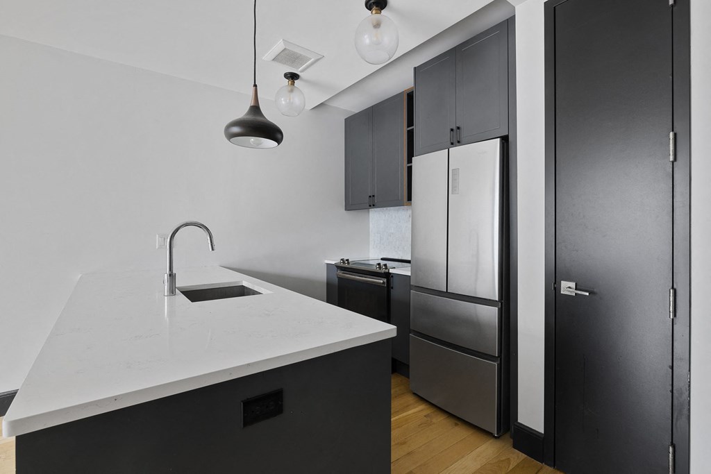 A modern kitchen with a white countertop and black cabinets.